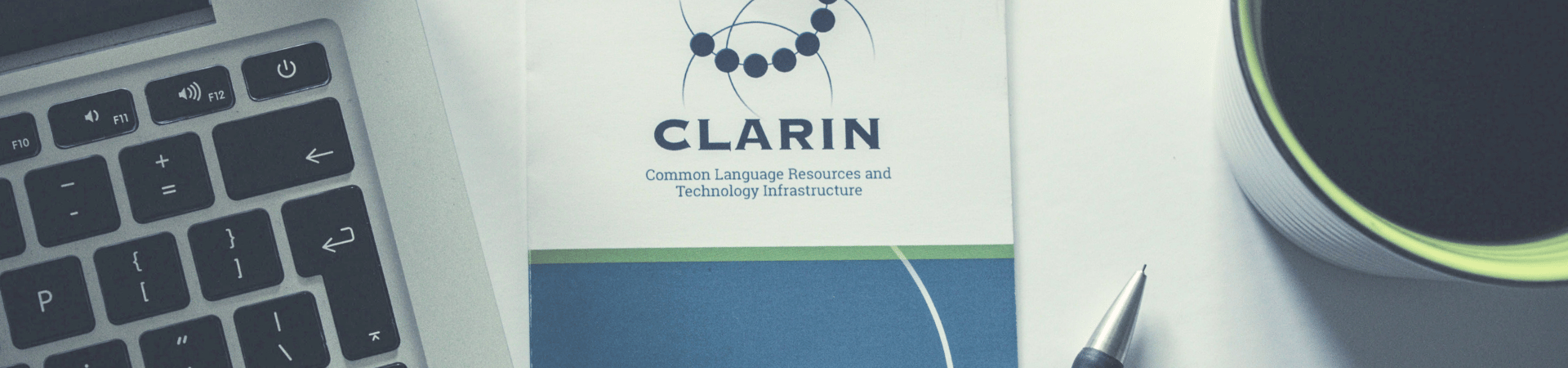 A photo of the CLARIN flyer next to a coffee, laptop and pen