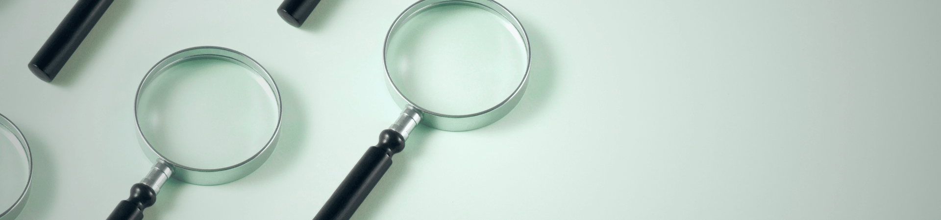 A photo of magnifying glasses on light green background